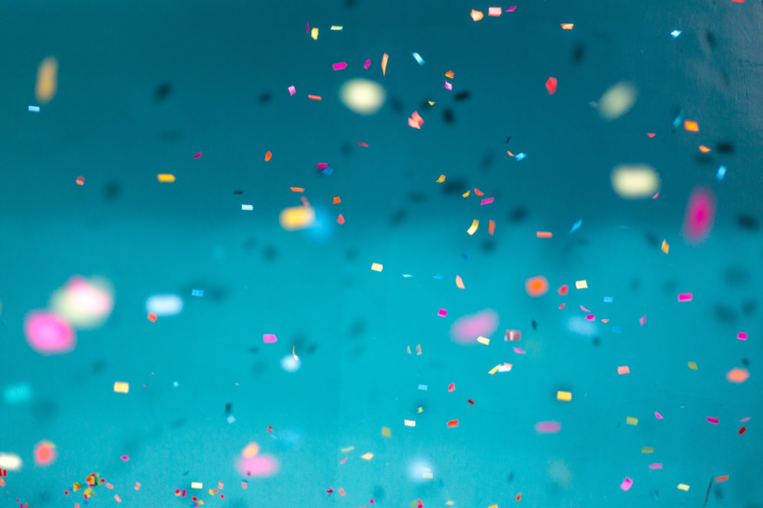 A blue background with multicoloured confetti falling in front of it