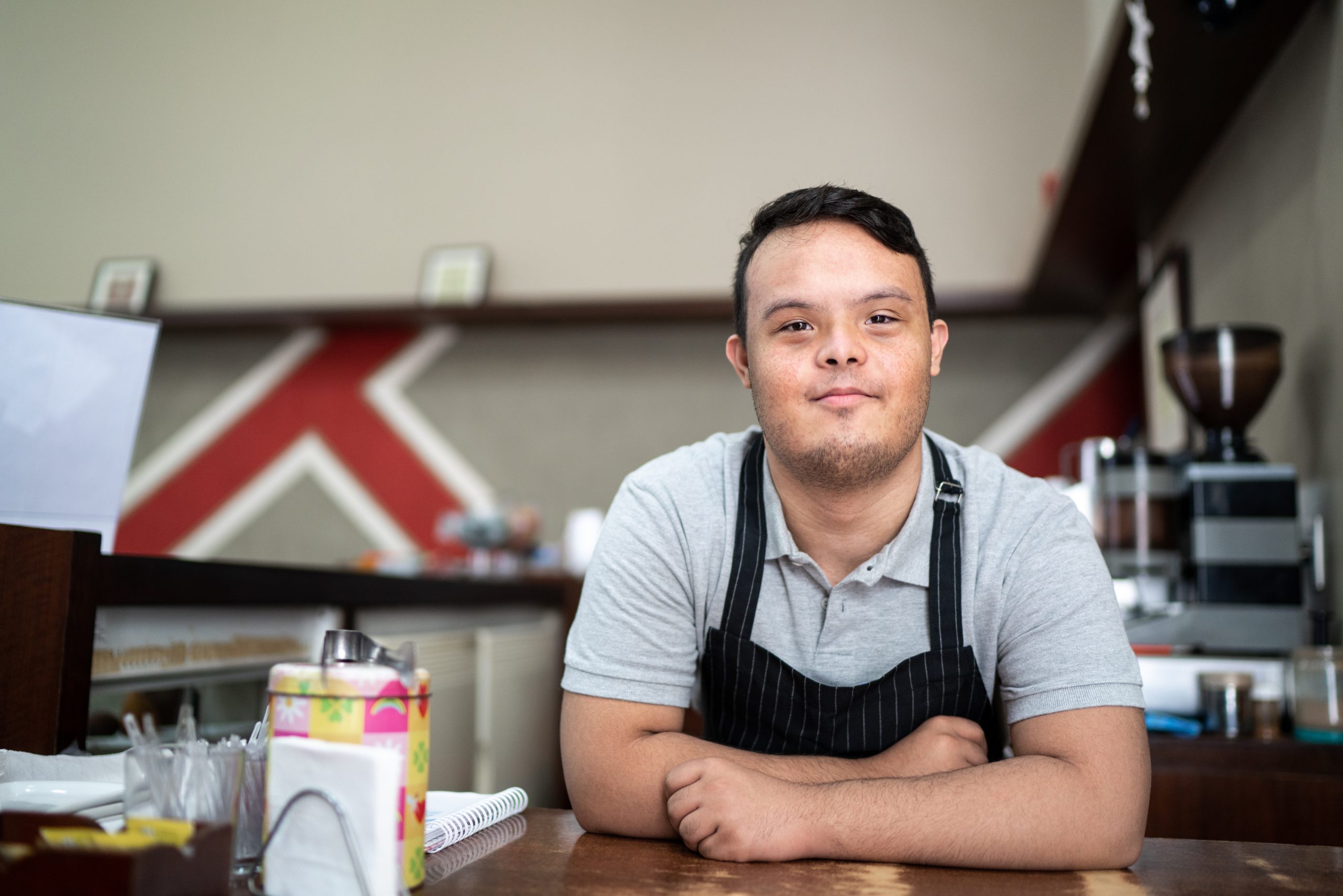 A photo of a young man with Downs Syndrome working behind the counter at a cafe